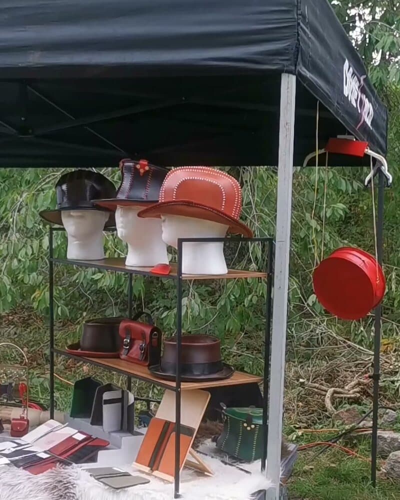Mon stand sous la tente noire : chapeaux sur leurs têtes, sacs et pièces sur les étagères